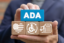 An Employer's Guide to FMLA and ADA with four cubes.  The top cube is blue with 'A.D.A' in white letter.  Bottom three cubes have a heart with an American flag inside the heart outline, a stickfigure person in a wheelchair with four arrorws around them, and a scale on the left of an outlined form.